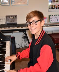 A young person playing a keyboard piano indoors.
