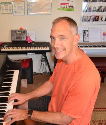 Man smiling while playing piano indoors.
