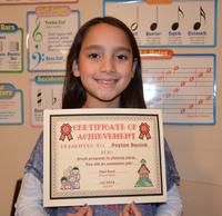 Young girl proudly holding a certificate of achievement.