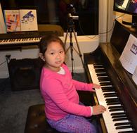 A young girl playing the piano indoors.