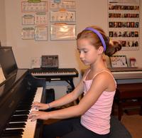 Young girl playing piano focused in a cozy room.