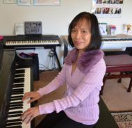 A woman in a purple sweater playing the piano indoors.