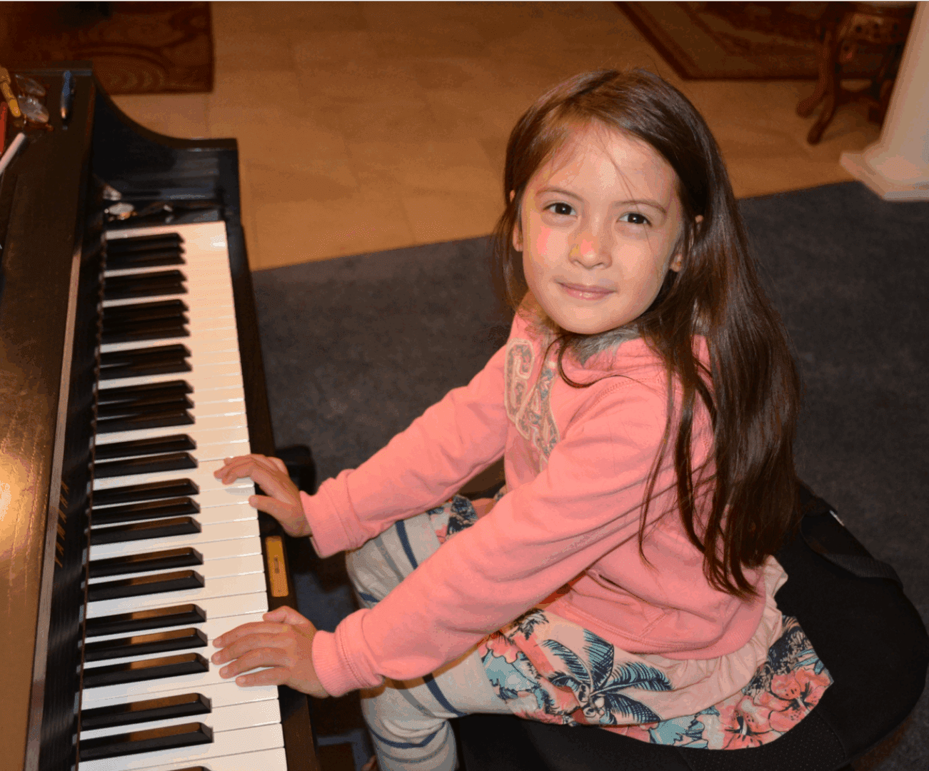 Young girl playing piano with a smile.