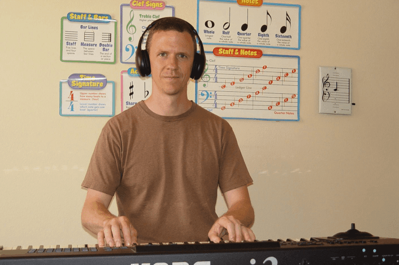 A man plays keyboard wearing headphones in a music room.