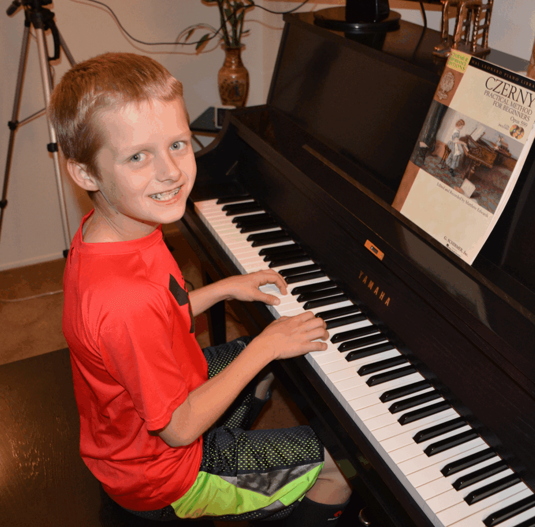 Child playing piano with sheet music.