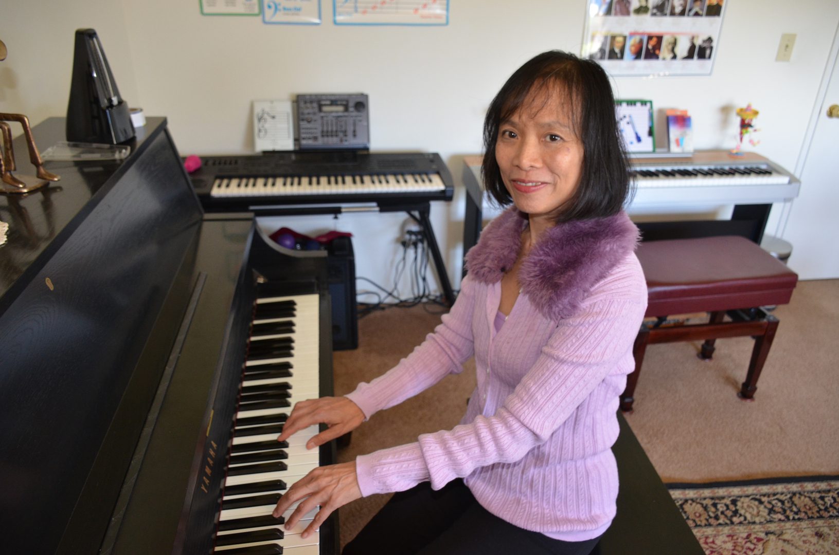 Woman playing piano in a cozy room with keyboard in the background.