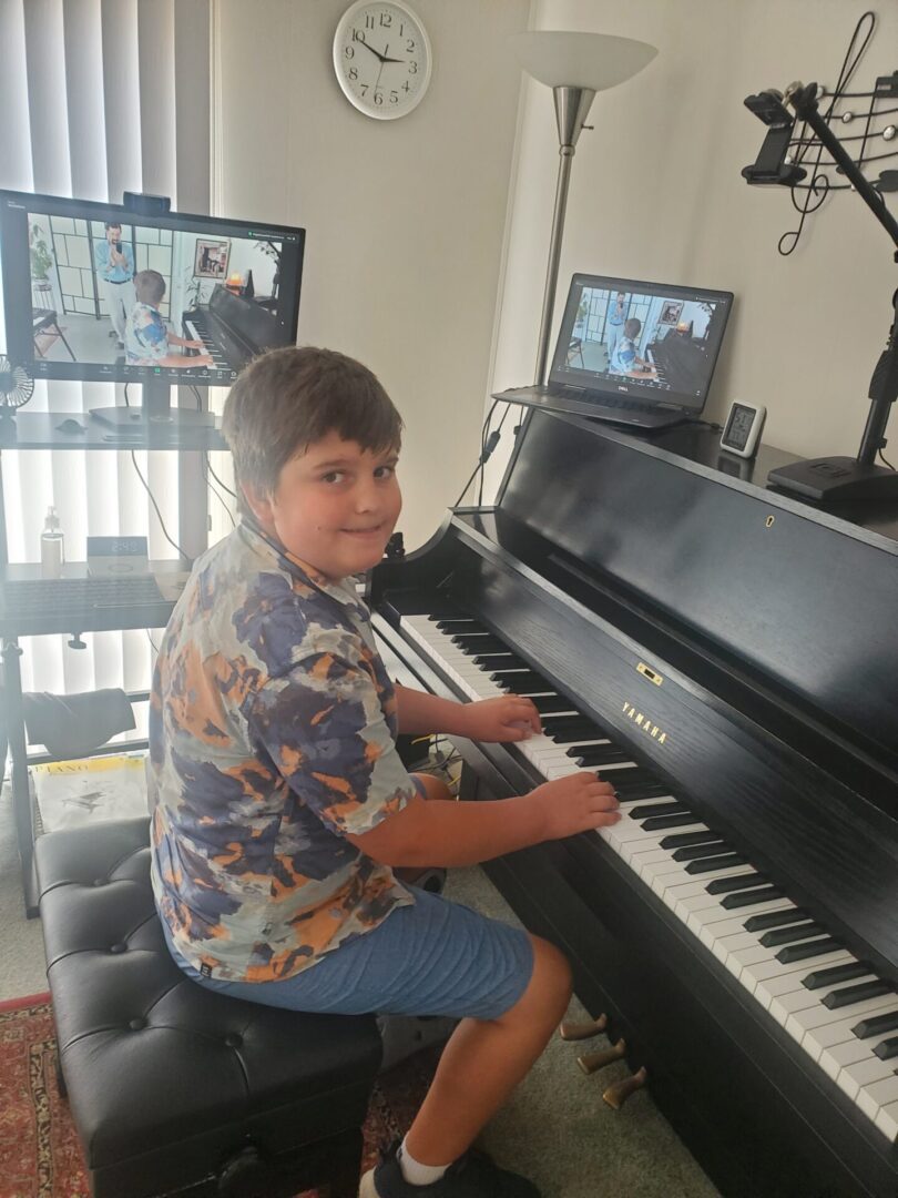 Young boy playing piano indoors near window with natural light.