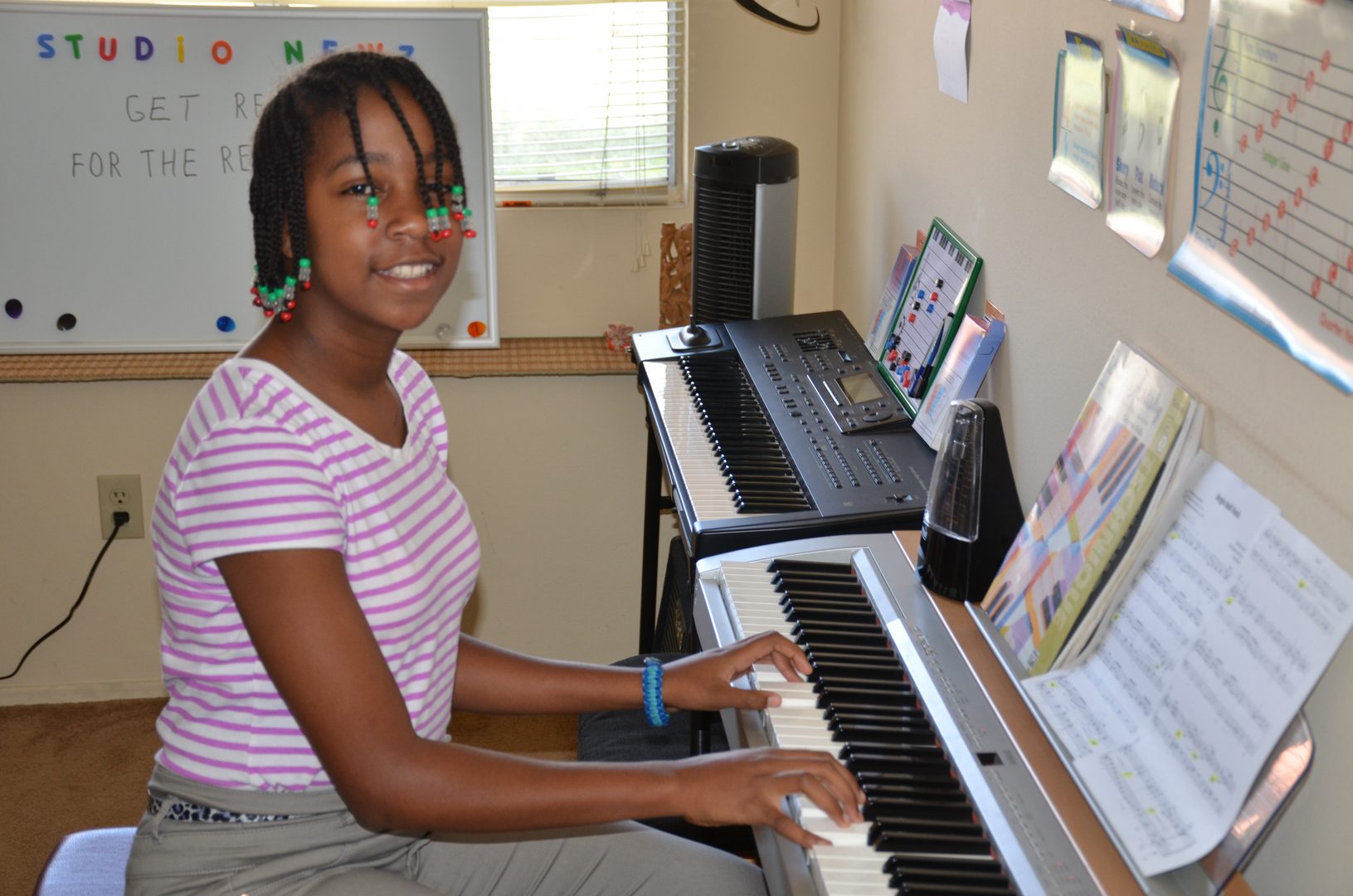 Young girl playing keyboard piano in a bright room.