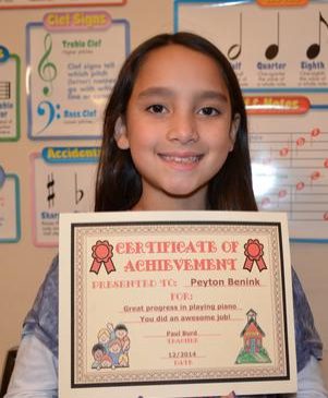 A young girl proudly holding her Certificate of Achievement.