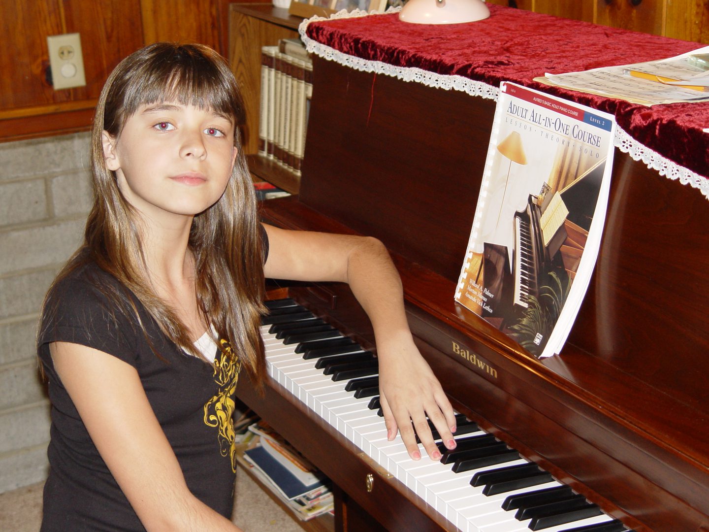 Young girl playing piano with sheet music.