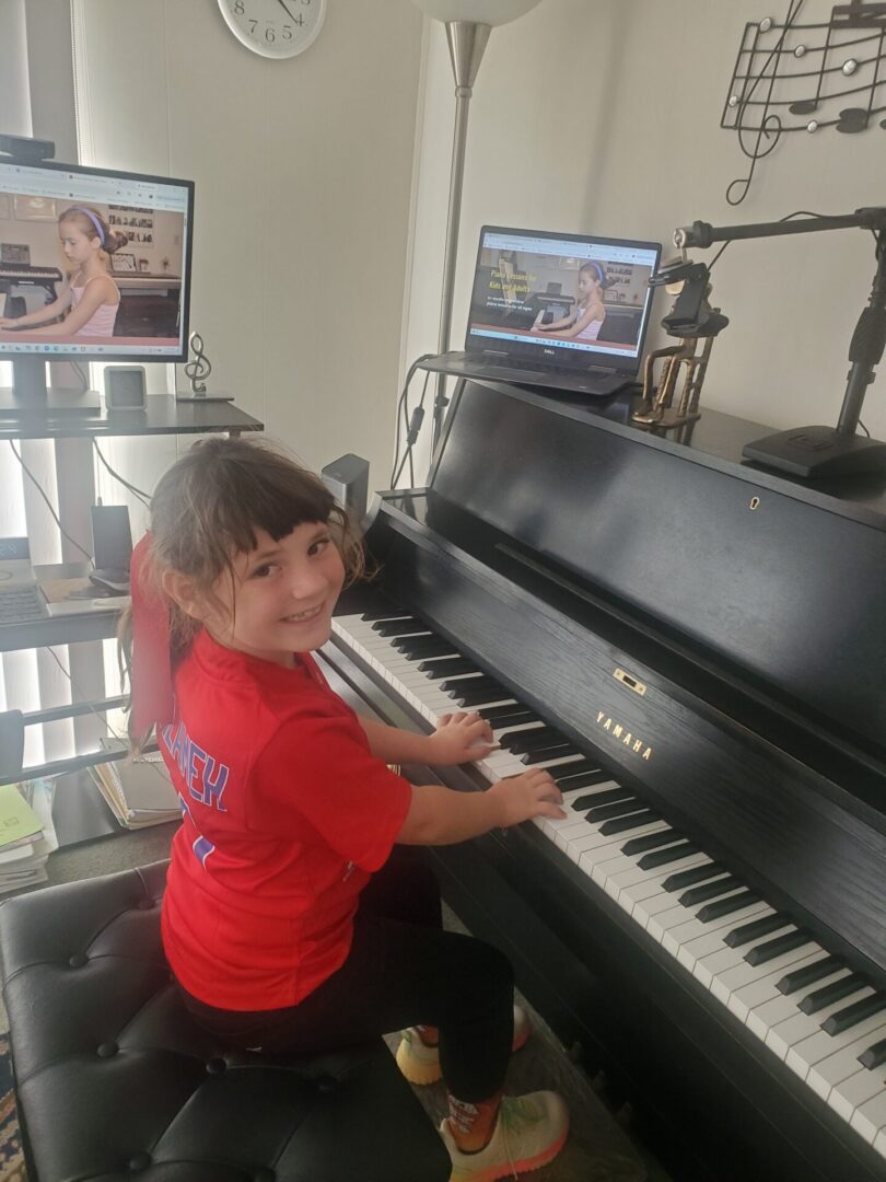 A young girl smiling while playing piano
