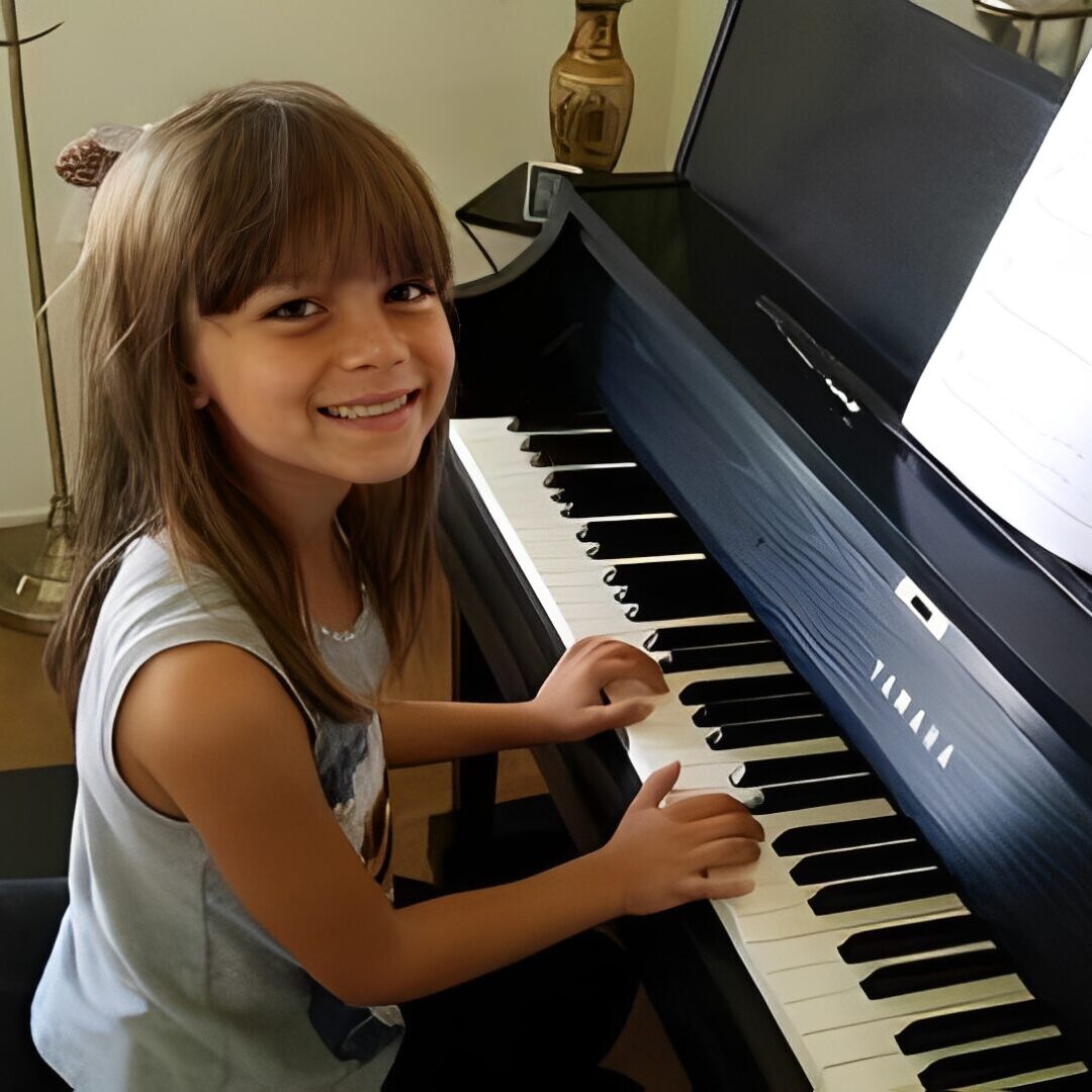 Girl smiling while playing the piano.